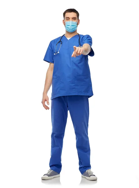 Man läkare i blå skurar och mask pekar finger — Stockfoto