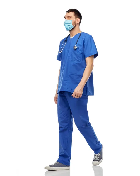 Mannelijke arts in blauw uniform en masker lopen — Stockfoto