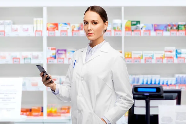 Doctora con smartphone en farmacia — Foto de Stock
