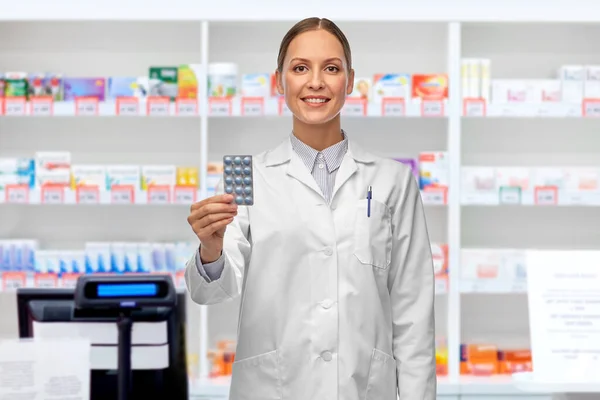 Sorridente médico feminino segurando medicina na farmácia — Fotografia de Stock