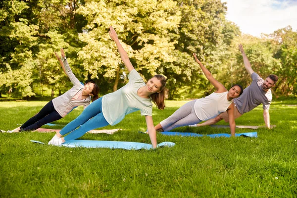 Grupo de personas haciendo yoga en el parque de verano — Foto de Stock