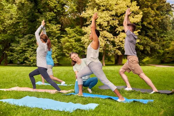 Groep mensen die yoga doen met instructeur in het park — Stockfoto