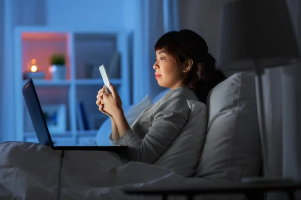 Mujer asiática con smartphone en la cama por la noche — Foto de Stock
