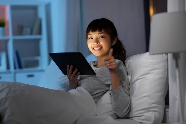 Mulher asiática com tablet pc na cama em casa à noite — Fotografia de Stock