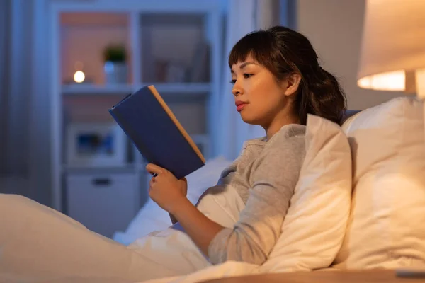 Joven asiático mujer leyendo libro en cama en casa —  Fotos de Stock