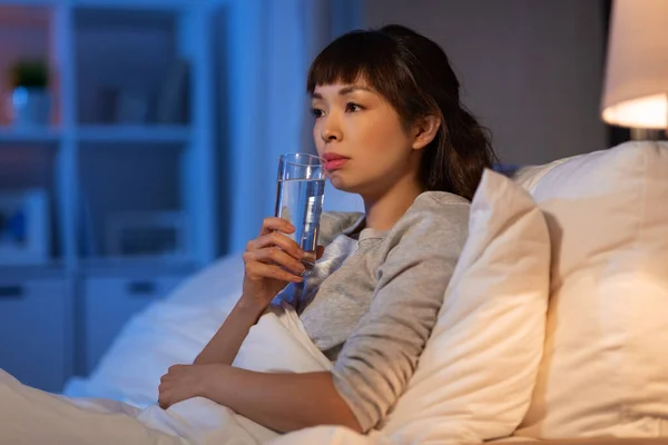 Asiático mujer beber agua en la noche en cama —  Fotos de Stock