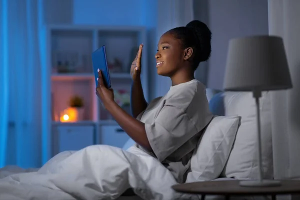 Женщина с планшетным ПК с видеозвонком в постели — стоковое фото