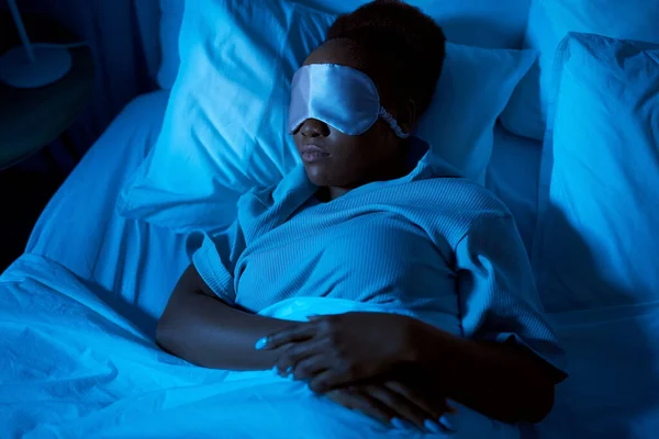 Mujer africana durmiendo en la cama en casa por la noche —  Fotos de Stock