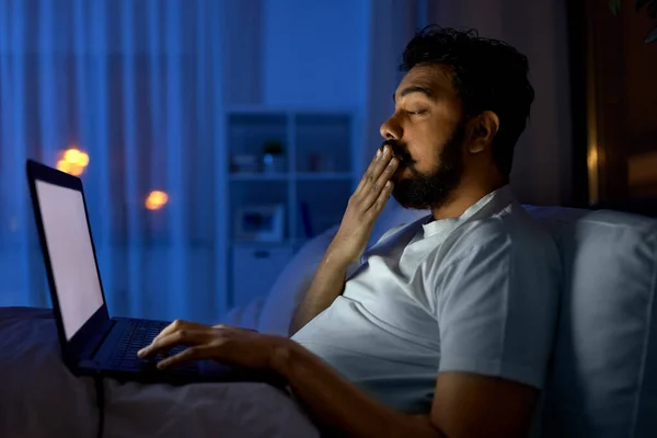 Indiaanse man met laptop in bed thuis 's nachts — Stockfoto