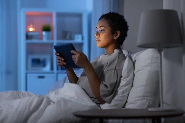 Mujer con tableta pc en la cama en casa por la noche — Foto de Stock
