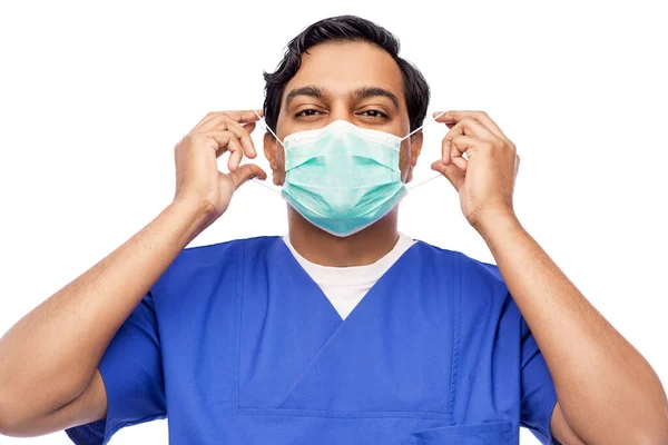 Indiana masculino médico em azul uniforme colocando máscara em — Fotografia de Stock