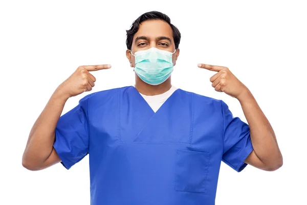 Indiano maschio medico in uniforme blu mostrando maschera — Foto Stock