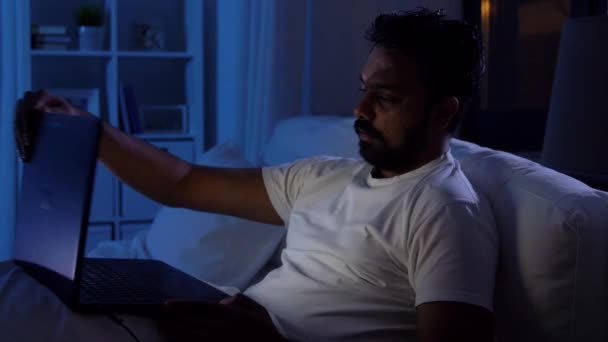 Indian man öppna laptop i sängen hemma på natten — Stockvideo