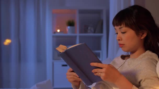 Junge Frau liest Buch zu Hause im Bett — Stockvideo