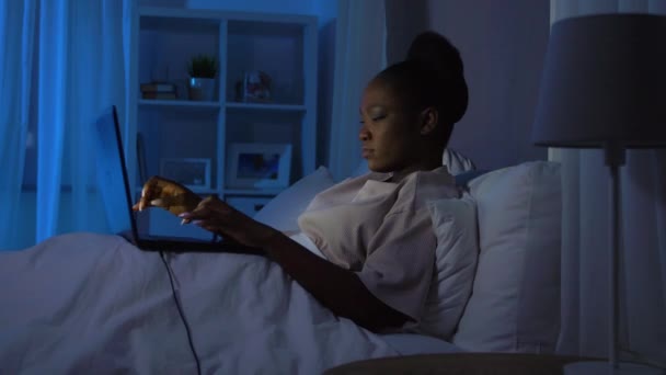 Donna africana che utilizza il computer portatile a letto a casa di notte — Video Stock