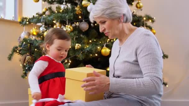 Grootmoeder en baby meisje opening kerstcadeau — Stockvideo