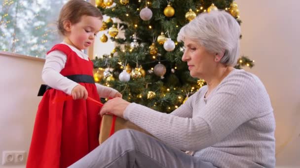 Grootmoeder en baby meisje opening kerstcadeau — Stockvideo