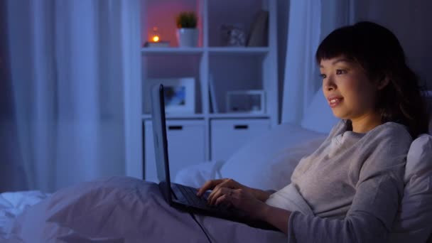 Mujer con portátil en la cama en casa por la noche — Vídeo de stock