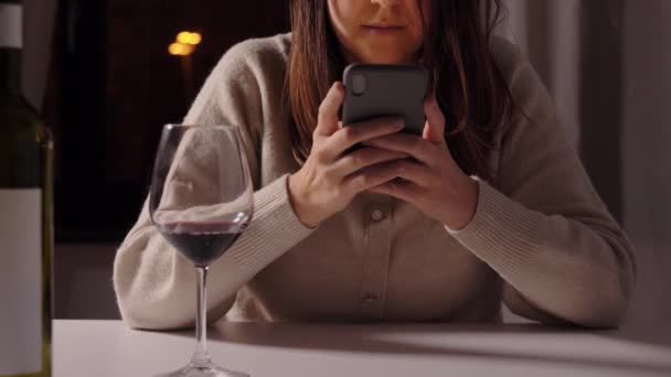 Vrouw alcoholist met telefoon drinken wijn thuis — Stockvideo