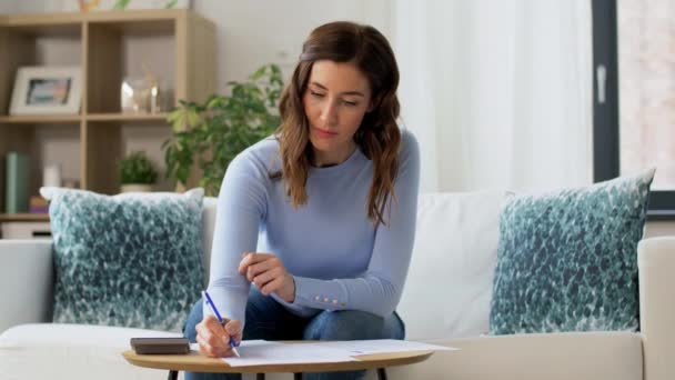 Mulher com papéis e calculadora em casa — Vídeo de Stock