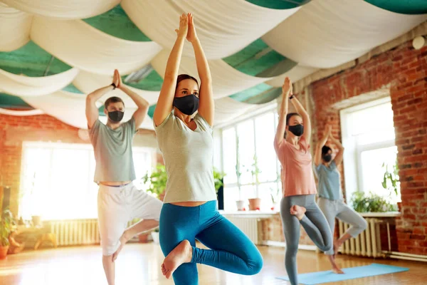 group of people in masks doing yoga at studio