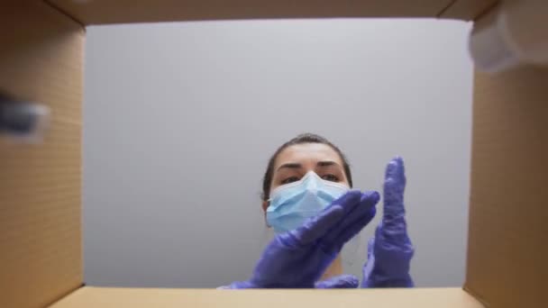 Kobieta w masce rozpakowywanie paczki z kosmetykami — Wideo stockowe