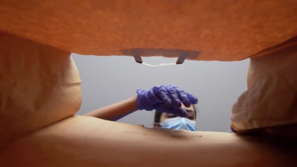 Vrouw in handschoenen en masker met voedsel in papieren zak — Stockvideo