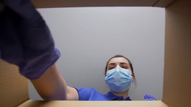 Vrouw in masker verpakking pakket doos met cosmetica — Stockvideo