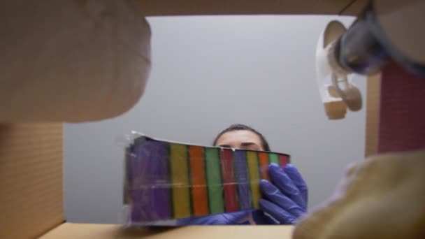 戴面具的妇女从盒子中取出清洁用品 — 图库视频影像