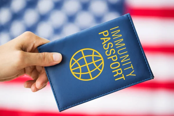 Mão segurando passaporte imunidade sobre bandeira americana — Fotografia de Stock