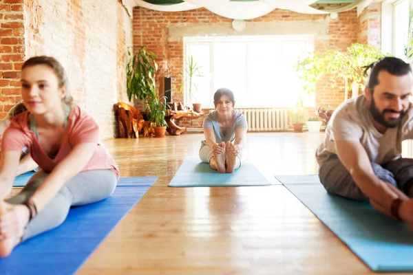 Grupo de personas haciendo yoga hacia adelante curva en el estudio —  Fotos de Stock