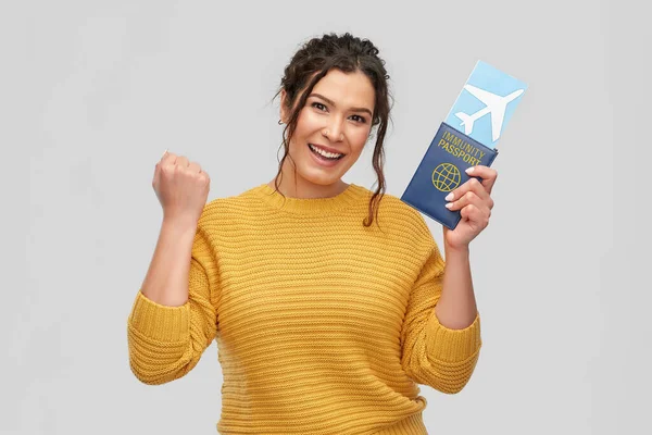 Mujer feliz con billete de avión y pasaporte de inmunidad — Foto de Stock