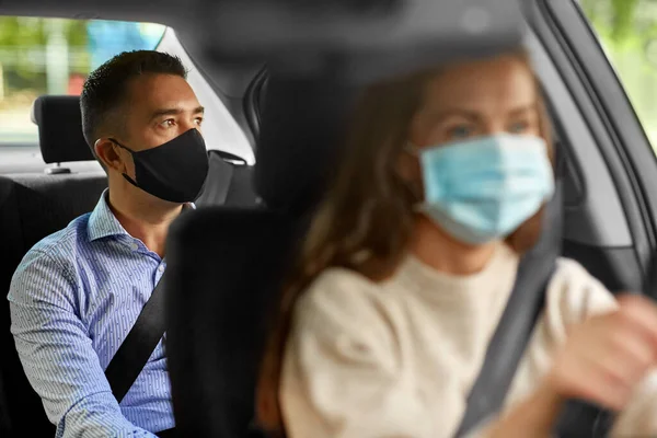 Женщина водитель в маске вождение автомобиля с пассажиром — стоковое фото