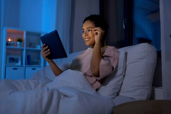 Mujer con tableta pc en la cama en casa por la noche — Foto de Stock