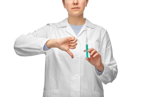 Médico fêmea com seringa mostrando polegares para baixo — Fotografia de Stock