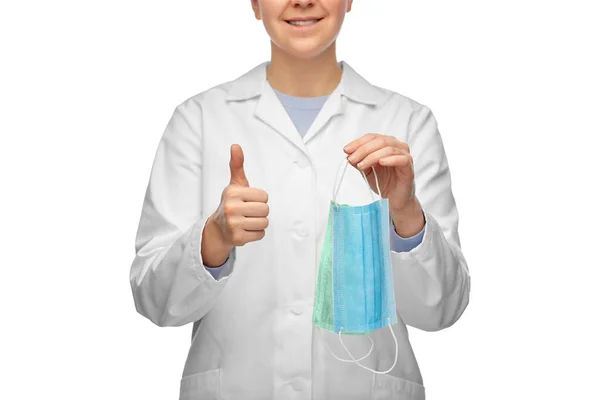Médico sorrindo com duas máscaras mostrando polegares para cima — Fotografia de Stock