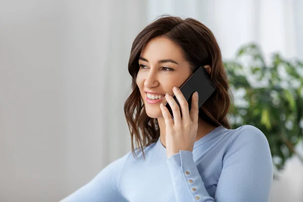 Glimlachende vrouw belt op smartphone thuis — Stockfoto