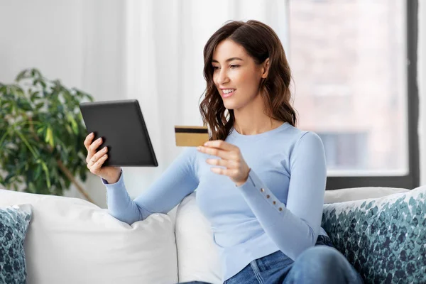 Szczęśliwa kobieta z tabletem i kartą kredytową w domu — Zdjęcie stockowe