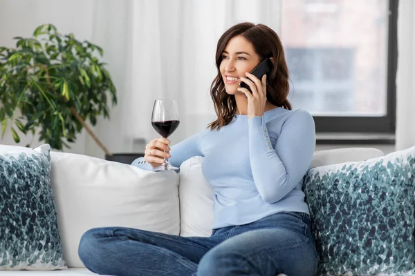 Mujer llamando en el teléfono inteligente y beber vino tinto — Foto de Stock