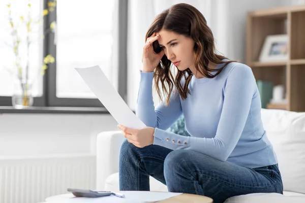 Gestresste vrouw met papieren en rekenmachine thuis — Stockfoto