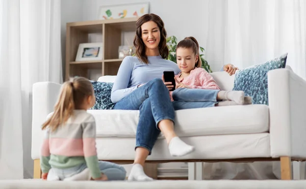 Mãe feliz e filhas com smartphone em casa — Fotografia de Stock