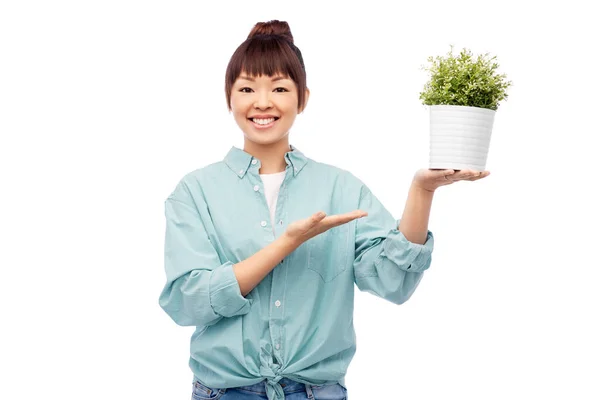 快乐的笑着的亚洲女人把花放在锅里 — 图库照片