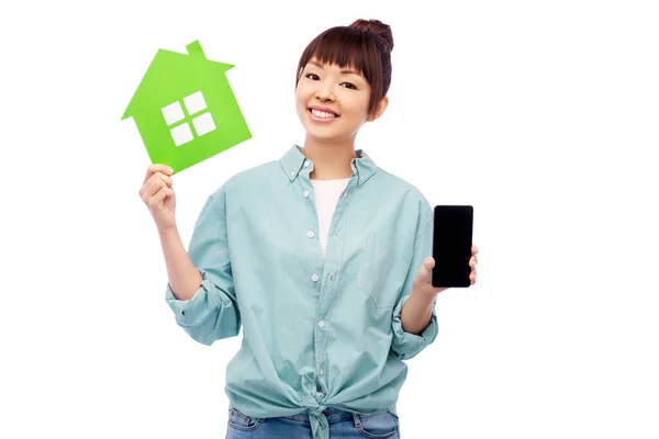 Улыбающаяся азиатская женщина держит зеленый дом — стоковое фото