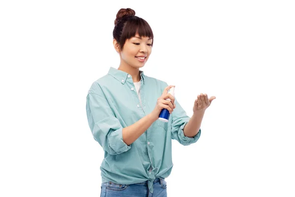 Счастливая улыбающаяся азиатка с помощью средства для дезинфекции рук — стоковое фото