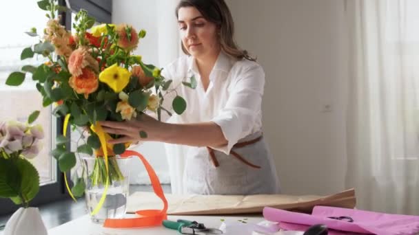Mujer envolviendo flores a papel artesanal en casa — Vídeos de Stock