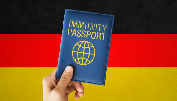 Tangan memegang paspor kekebalan atas bendera Jerman — Stok Foto