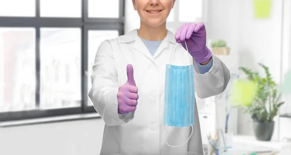 엄지손가락이 보이는 의료용 마스크를 쓰고 있는 여자 의사 — 스톡 사진