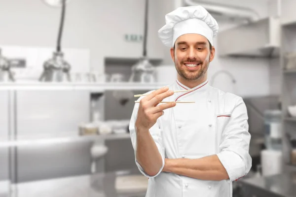 Glad manlig kock med ätpinnar i köket — Stockfoto