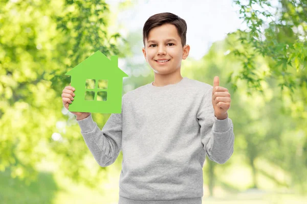 Yeşil evi olan gülümseyen ve baş parmak gösteren bir çocuk. — Stok fotoğraf