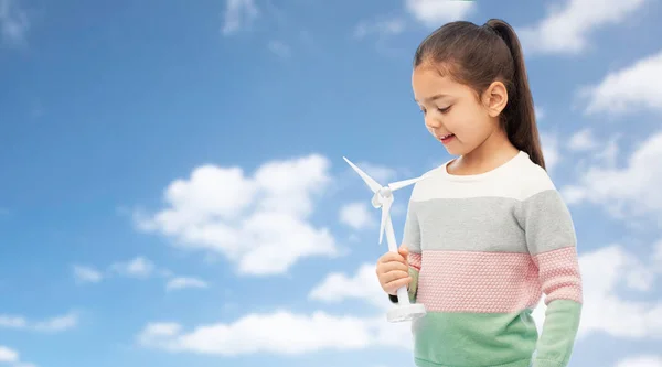 Sorridente ragazza con turbina eolica giocattolo sopra cielo blu — Foto Stock